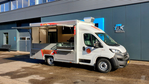 Zijaanzicht van een verkoopwagen voor loempia's, patat en snacks met geopende luifel