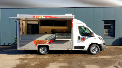 Zijaanzicht van een verkoopwagen voor loempia's, patat en snacks met geopende luifel