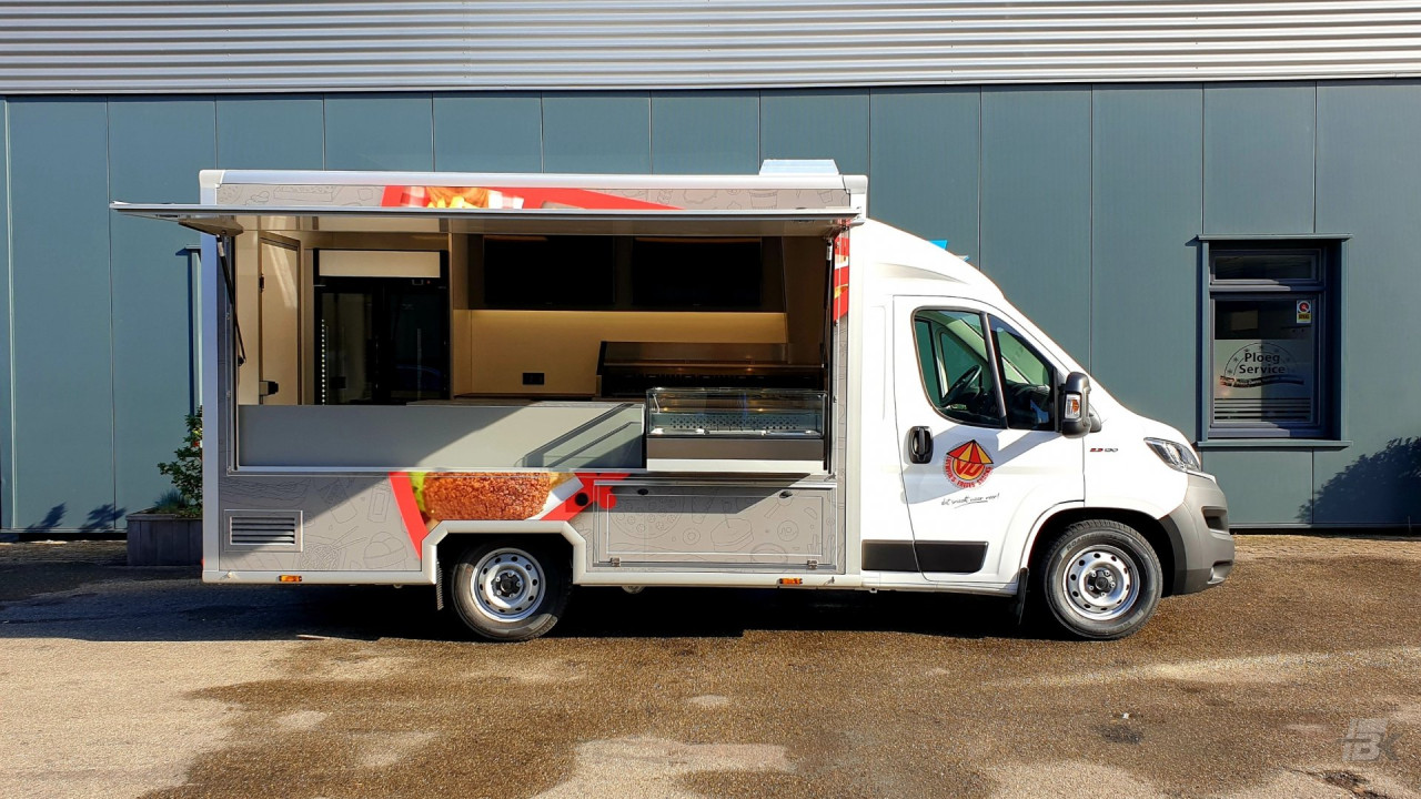 Zijaanzicht van een verkoopwagen voor loempia's, patat en snacks met geopende luifel