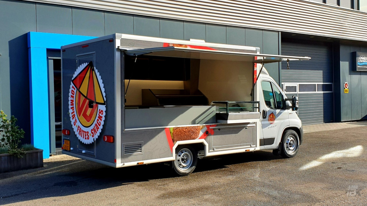 Zijaanzicht van een verkoopwagen voor loempia's, patat en snacks met geopende luifel