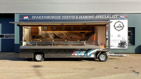 Zijaanzicht van een aanhangwagen voor vis met geopende luifel en zijbord