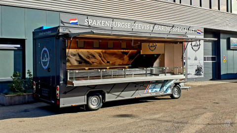 Zijaanzicht van een aanhangwagen voor vis met geopende luifel en zijbord