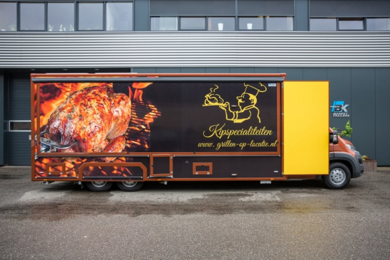 Zijaanzicht van een verkoopwagen voor kip aan het spit met gesloten luifel