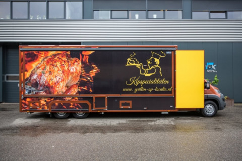 Zijaanzicht van een verkoopwagen voor kip aan het spit met gesloten luifel