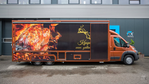 Zijaanzicht van een verkoopwagen voor kip aan het spit met gesloten luifel
