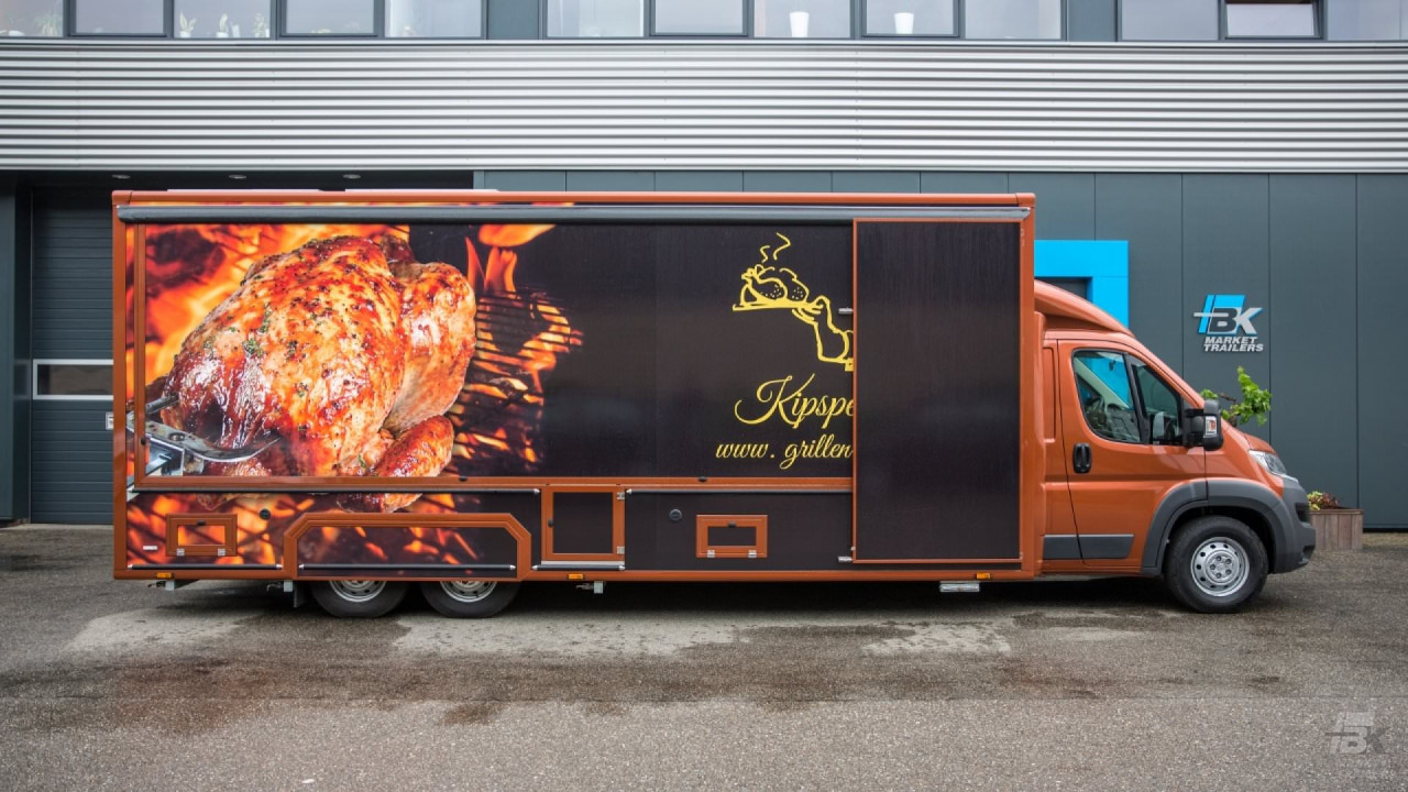 Zijaanzicht van een verkoopwagen voor kip aan het spit met gesloten luifel