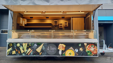 Zijaanzicht van een aanhangwagen voor kaas en olijven met geopende luifel