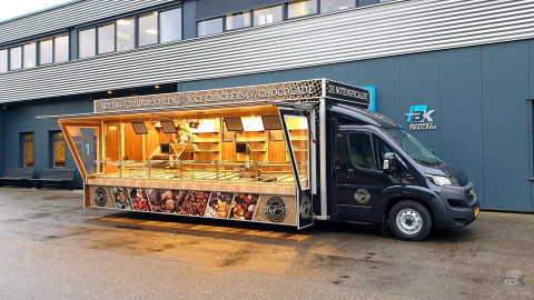 Zijaanzicht van een verkoopwagen voor noten met geopende luifel en zijborden