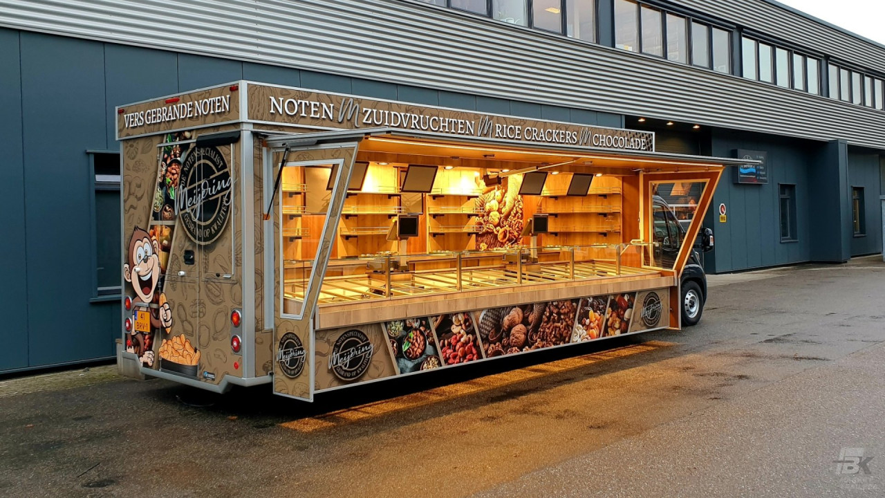 Zijaanzicht van een verkoopwagen voor noten met geopende luifel en zijborden