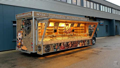Zijaanzicht van een verkoopwagen voor noten met geopende luifel en zijborden