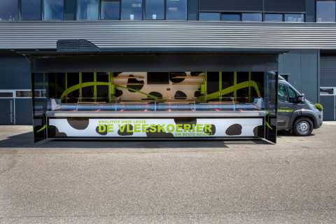 Zijaanzicht van een verkoopwagen voor vlees met geopende luifel en zijborden