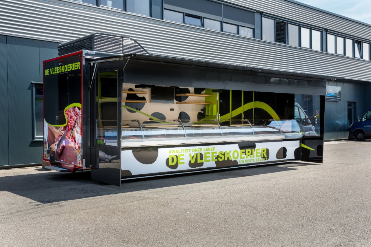 Zijaanzicht van een verkoopwagen voor vlees met geopende luifel en zijborden
