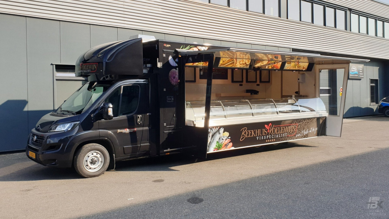 Zijaanzicht van een verkoopwagen voor vis met geopende luifel en zijborden