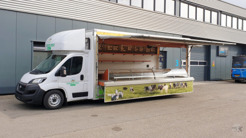 Zijaanzicht van een verkoopwagen voor kaas met geopende luifel