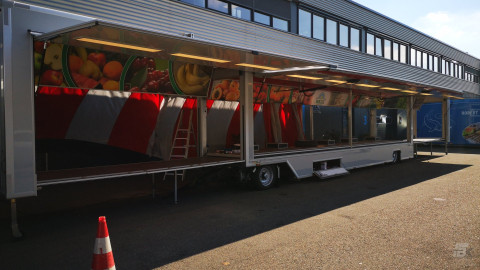 Zijaanzicht van een uitschuifbare aanhangwagen voor groente en fruit met geopende luifel