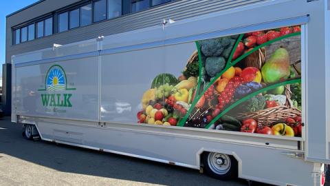 Zijaanzicht van een uitschuifbare aanhangwagen voor groente en fruit met gesloten luifel