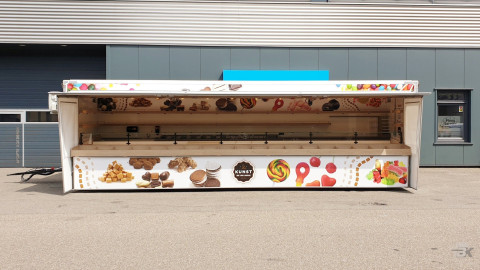 Zijaanzicht van een aanhangwagen voor drop, snoep en chocolade met geopende luifel en zijborden