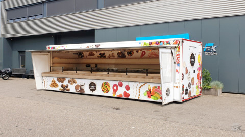 Zijaanzicht van een aanhangwagen voor drop, snoep en chocolade met geopende luifel en zijborden