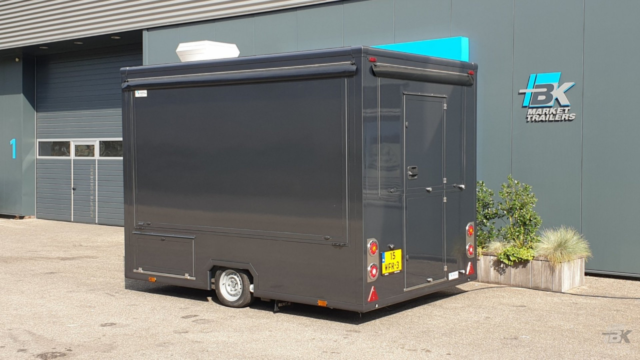 Zijaanzicht van een kleine aanhangwagen voor loempia's met gesloten luifel