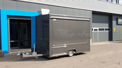 Zijaanzicht van een kleine aanhangwagen voor loempia's met gesloten luifel