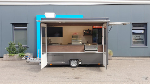 Zijaanzicht van een kleine aanhangwagen voor loempia's met geopende luifel en zijborden
