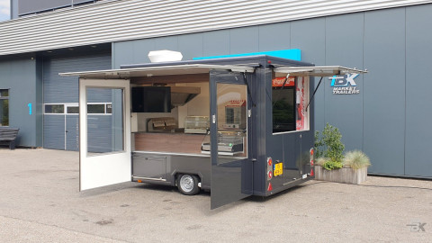 Zijaanzicht van een kleine aanhangwagen voor loempia's met geopende luifel en zijborden