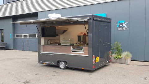 Zijaanzicht van een kleine aanhangwagen voor loempia's met geopende luifel