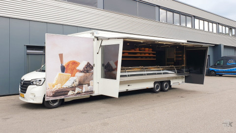 Zijaanzicht van een verkoopwagen voor kaas met geopende luifel en zijborden