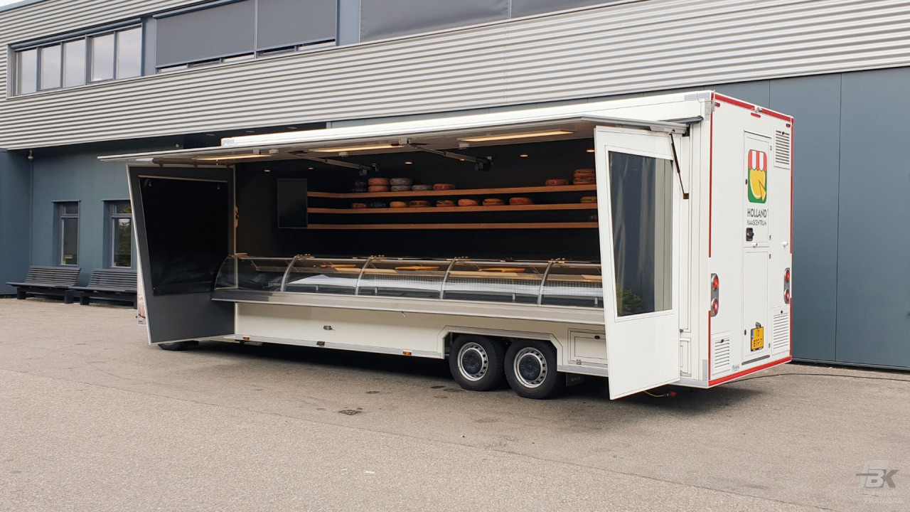 Zijaanzicht van een verkoopwagen voor kaas met geopende luifel en zijborden