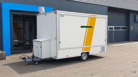 Zijaanzicht van een kleine aanhangwagen voor diverse branches met gesloten luifel