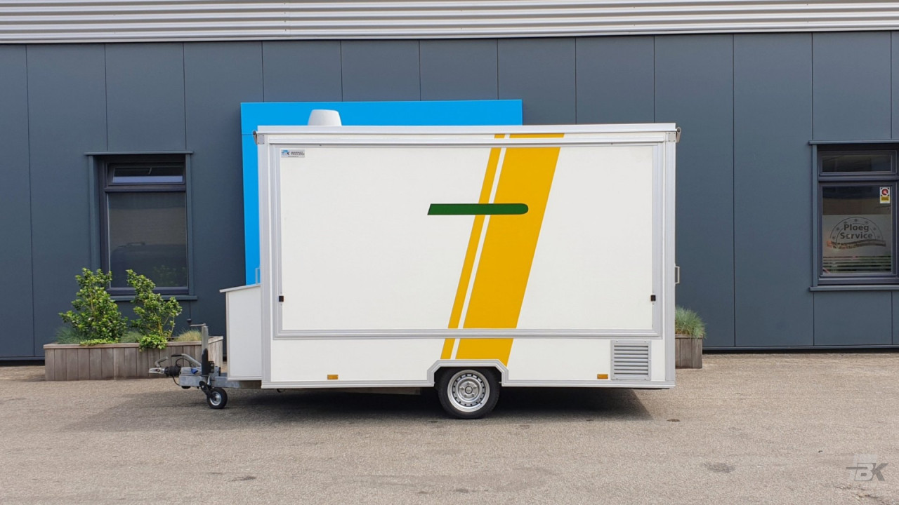 Zijaanzicht van een kleine aanhangwagen voor diverse branches met gesloten luifel