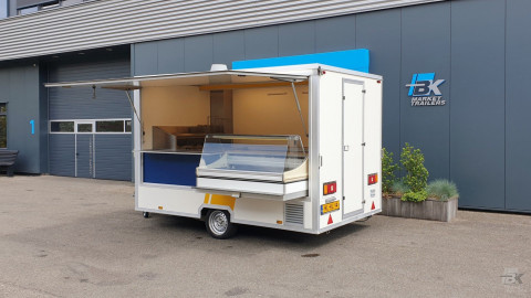 Zijaanzicht van een kleine aanhangwagen voor diverse branches met geopende luifel