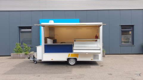 Zijaanzicht van een kleine aanhangwagen voor diverse branches met geopende luifel