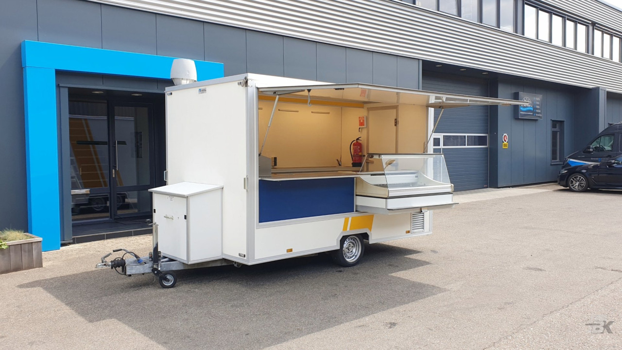 Zijaanzicht van een kleine aanhangwagen voor diverse branches met geopende luifel