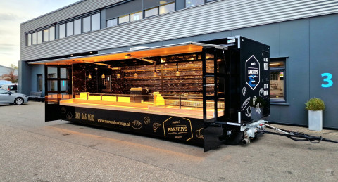 Zijaanzicht van een aanhangwagen voor brood en banket met geopende luifel en zijborden