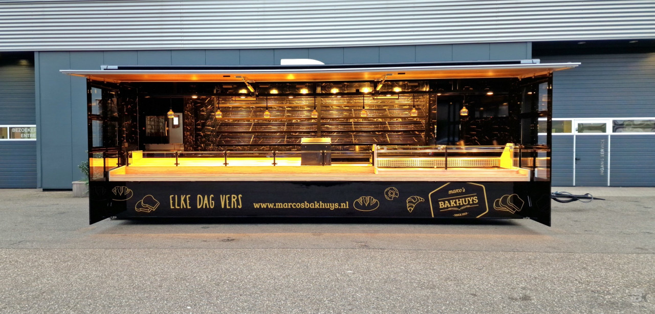 Zijaanzicht van een aanhangwagen voor brood en banket met geopende luifel en zijborden