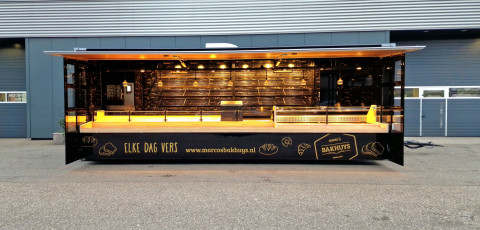 Zijaanzicht van een aanhangwagen voor brood en banket met geopende luifel en zijborden