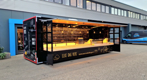 Zijaanzicht van een aanhangwagen voor brood en banket met geopende luifel en zijborden