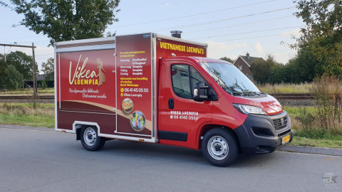 Zijaanzicht van een verkoopwagen voor loempia's met gesloten luifel