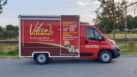 Zijaanzicht van een verkoopwagen voor loempia's met gesloten luifel