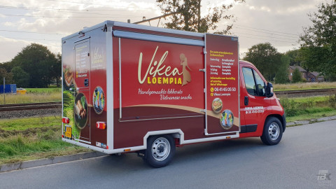 Zijaanzicht van een verkoopwagen voor loempia's met gesloten luifel