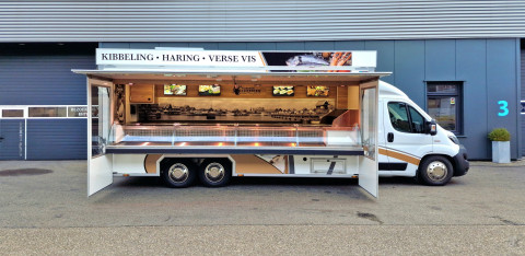 Zijaanzicht van een verkoopwagen voor vis met geopende luifel en zijborden