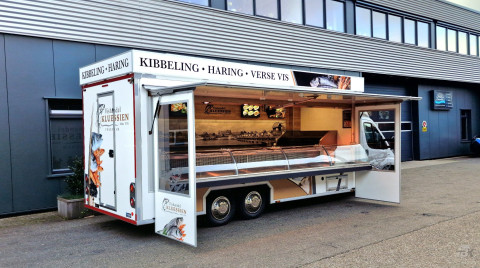 Zijaanzicht van een verkoopwagen voor vis met geopende luifel en zijborden