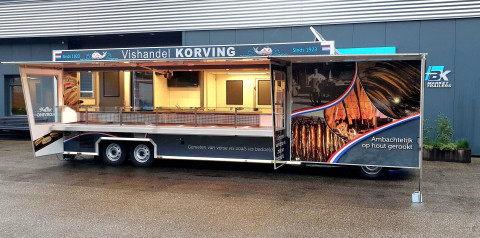 Zijaanzicht van een verkoopwagen voor vis met geopende luifel en zijborden