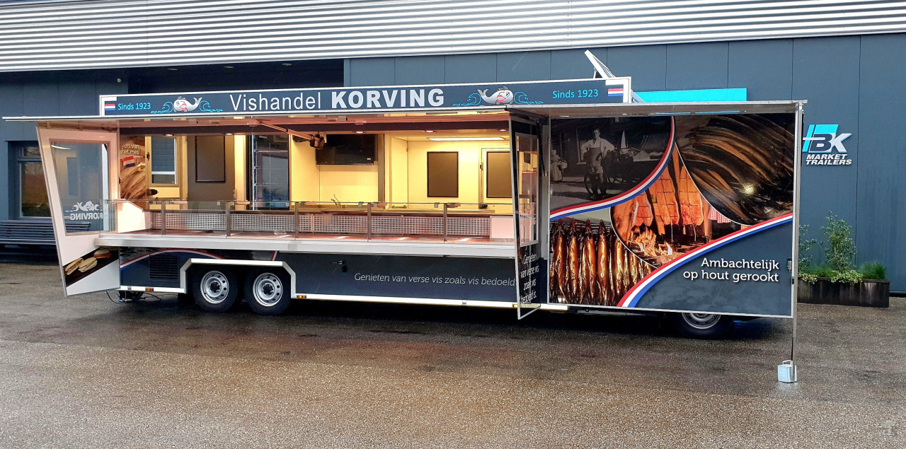 Zijaanzicht van een verkoopwagen voor vis met geopende luifel en zijborden