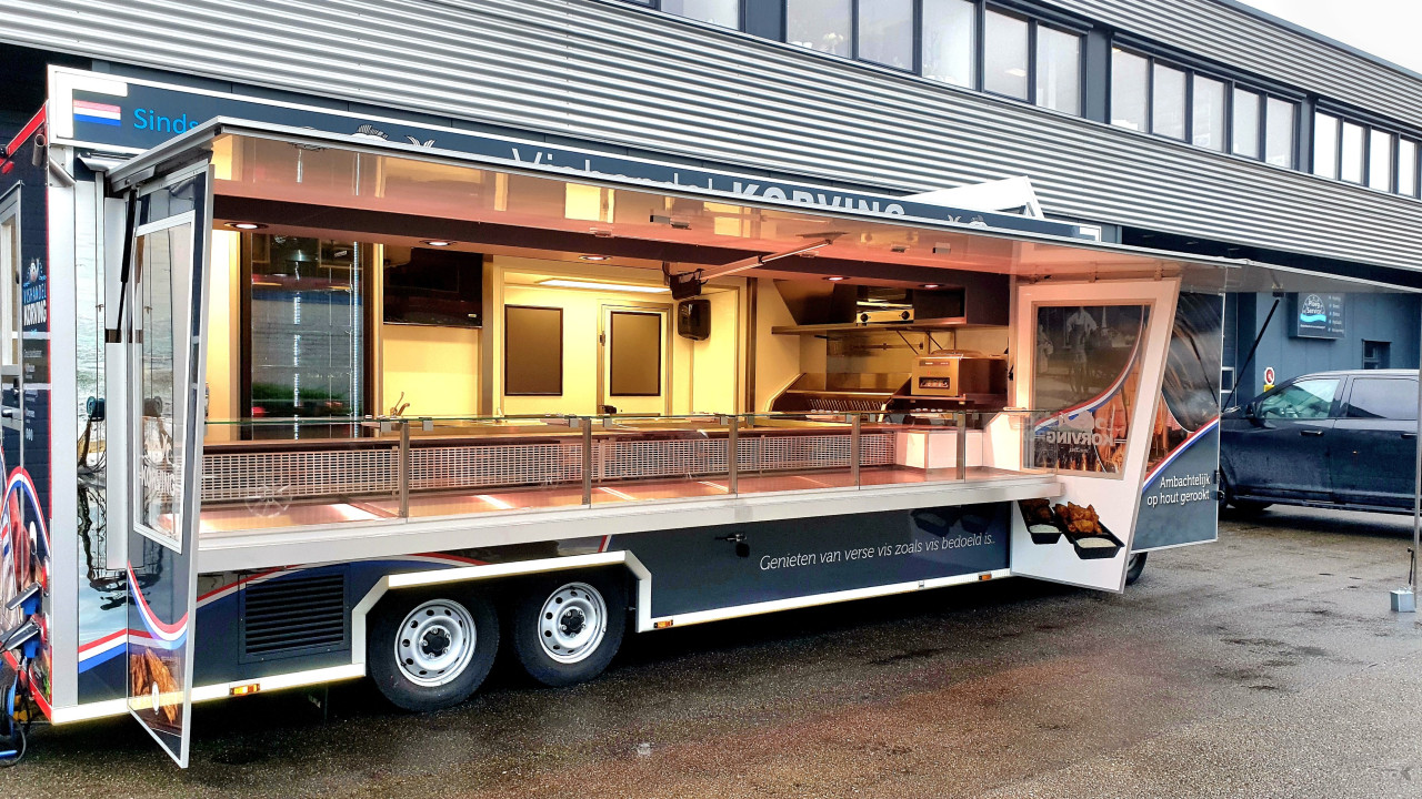 Zijaanzicht van een verkoopwagen voor vis met geopende luifel en zijborden