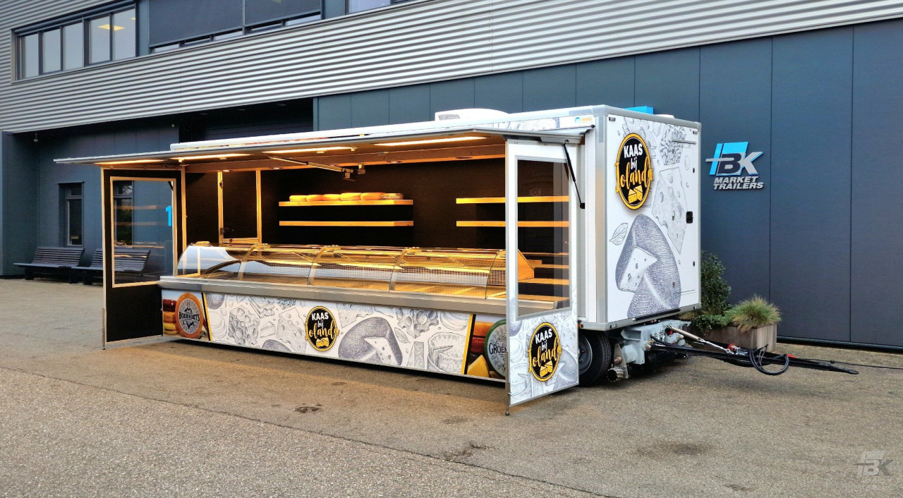 Zijaanzicht van een verkoopwagen voor kaas met geopende luifel en zijborden