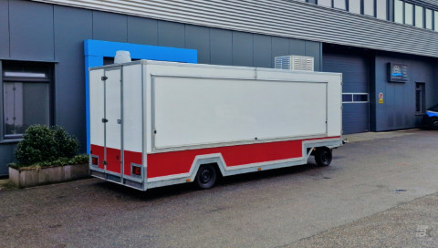 Zijaanzicht van een aanhangwagen voor diverse branches met gesloten luifel