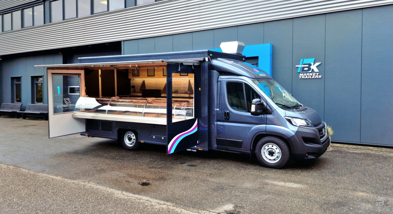 Zijaanzicht van een verkoopwagen voor vis met geopende luifel en zijborden