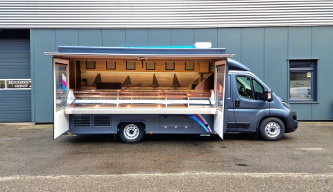Zijaanzicht van een verkoopwagen voor vis met geopende luifel en zijborden
